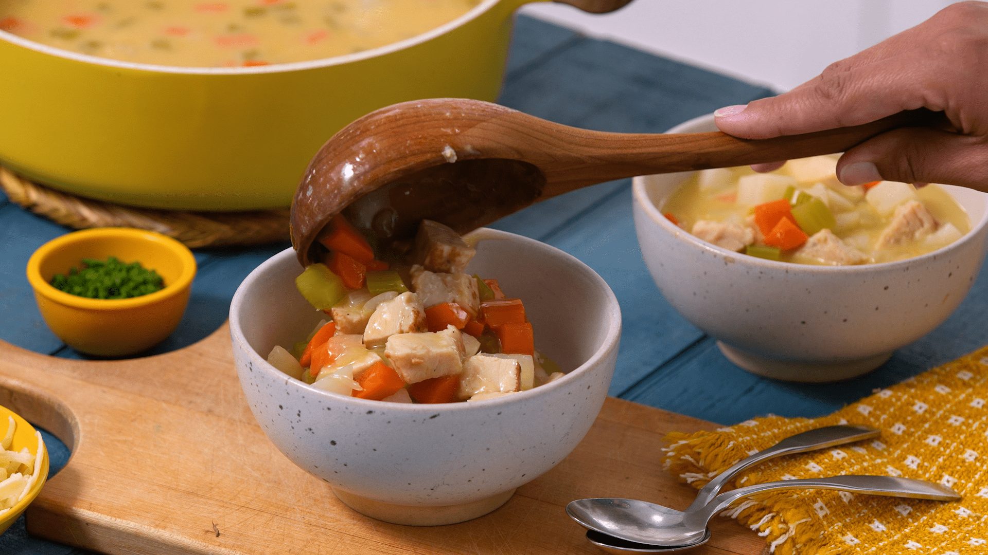 Ladeling Creamy Chicken Potato Chowder into soup bowls