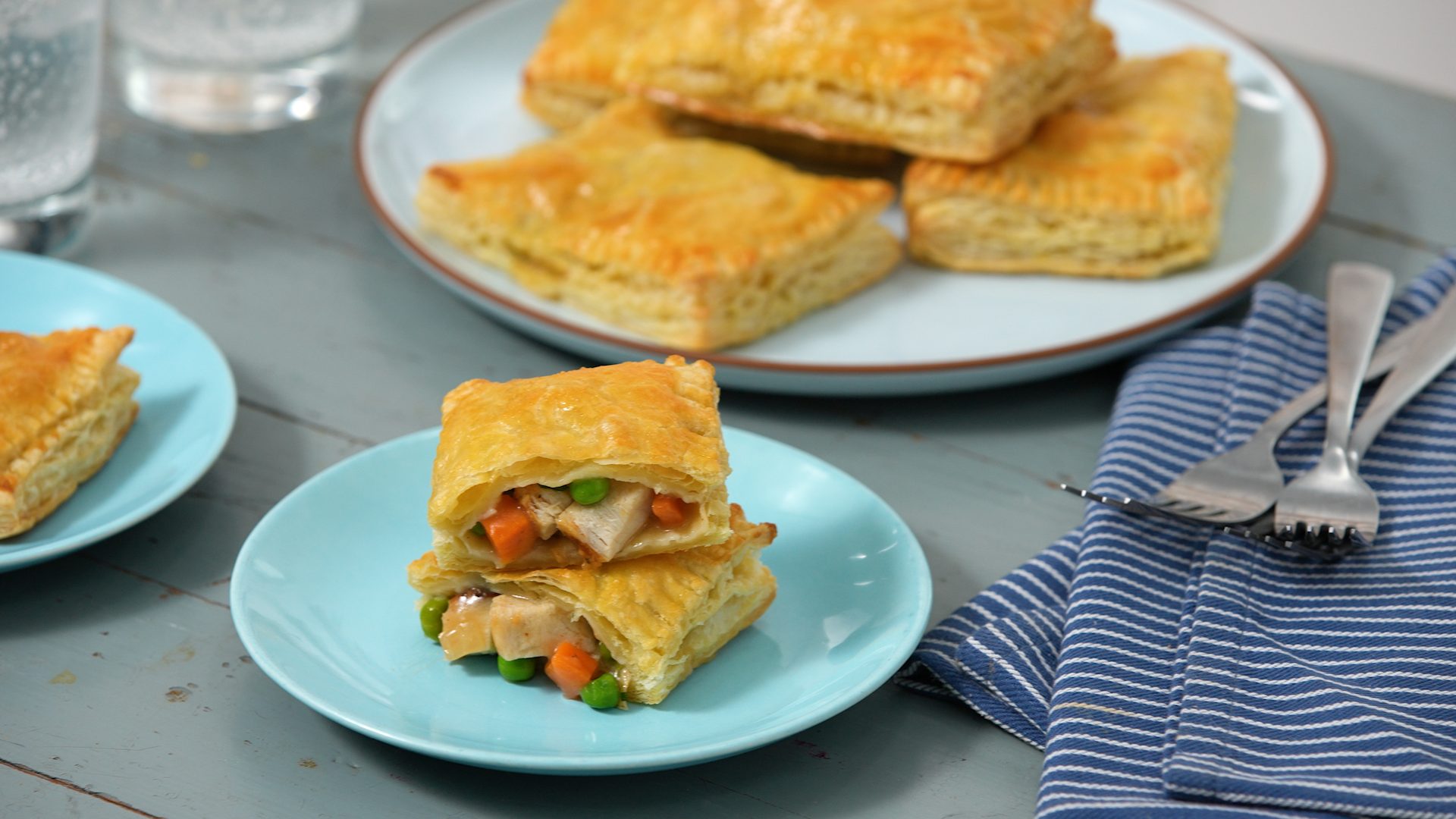 Image of chicken pot pie pockets on plates with one cut open showing meat, veggies and gravy inside